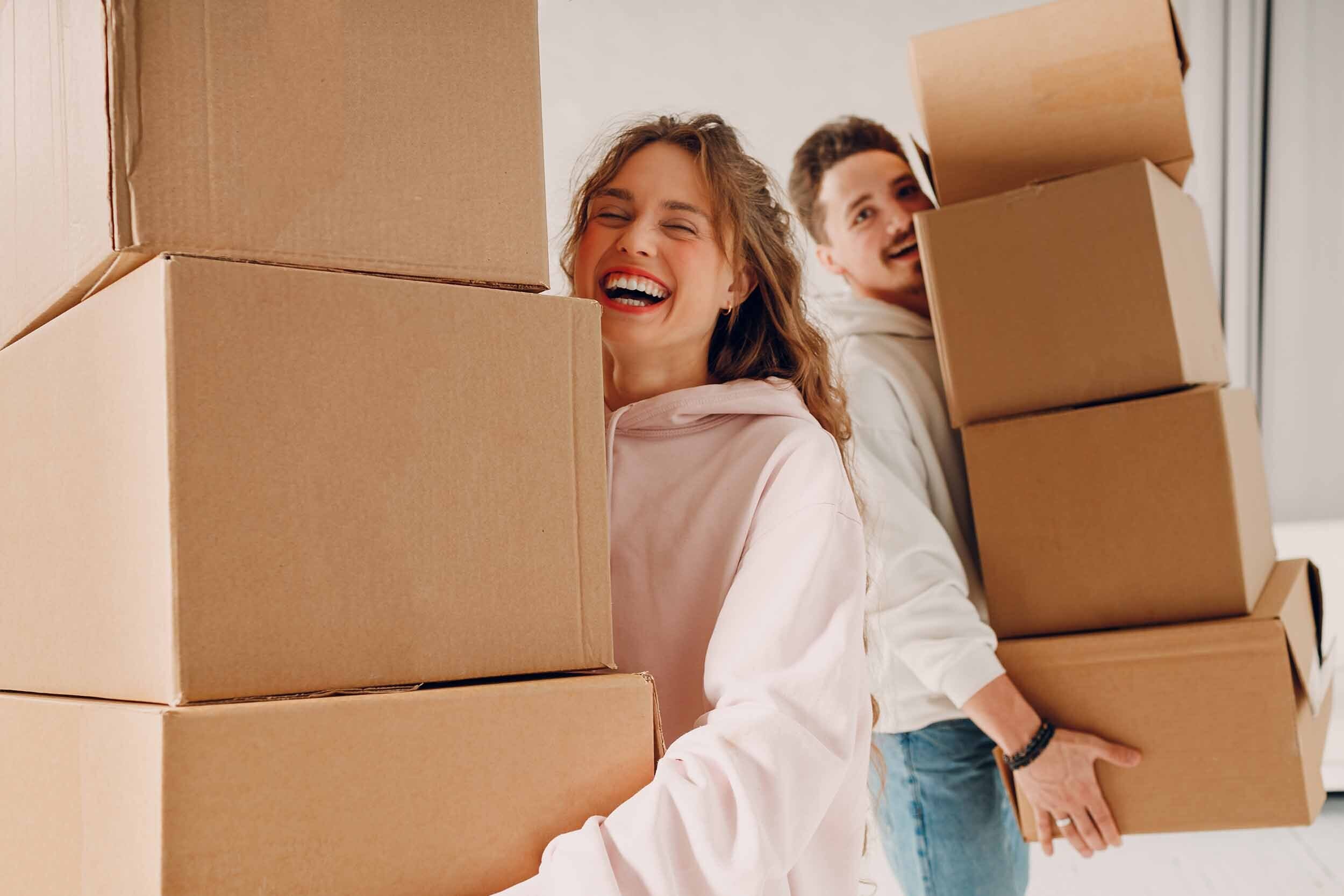 Happy, smiling couple carrying moving boxes